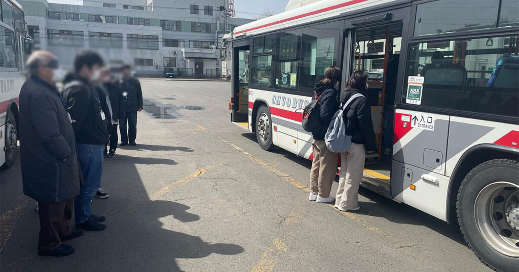 バスに乗り込むのをサポートする女性と受講生達