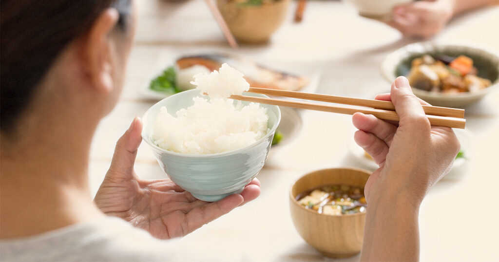 ホカホカご飯を箸で食べる女性