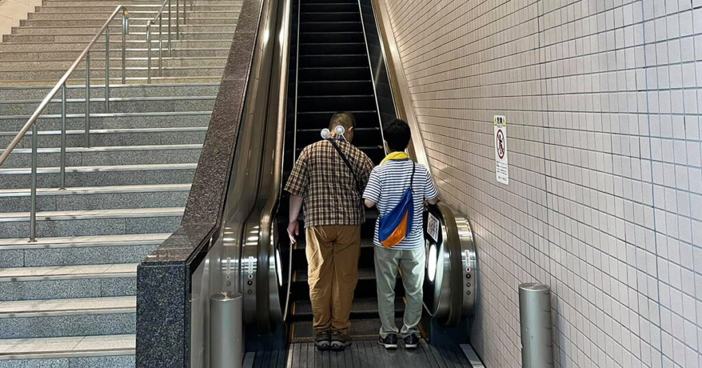 エスカレーターに乗るのをサポートする男性