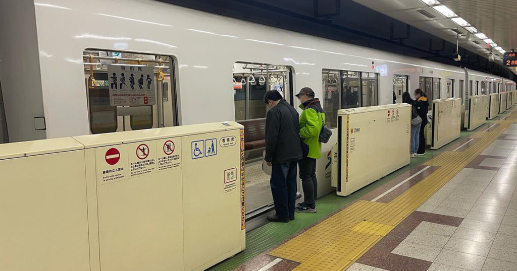 地下鉄に乗り込むのをサポートする男性